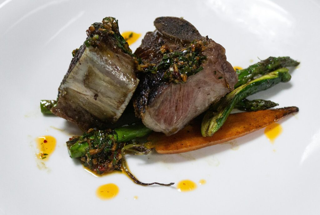 Close-up of a gourmet steak dish with asparagus and carrots, showcasing culinary art.